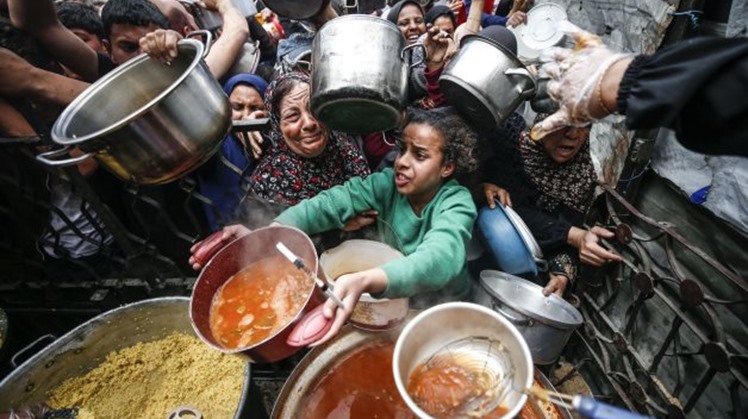 Residents gather to receive free food from a charitable kitchen in Gaza City - Photo: WAFA